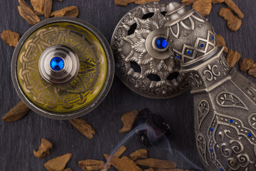Silver Oriental Artisitc Arabian Oud Perfume / Arabian Oud Perfume with Oud Scented Wood burned in the background with Scented Smoke in the Air 