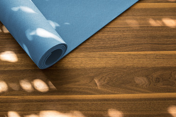 Yoga mat on a wooden background. Equipment for yoga. Concept healthy lifestyle. Lots of copyspace