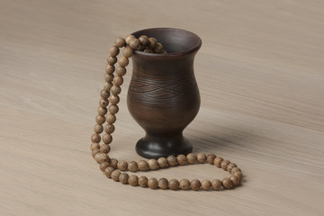 Clay jug with wooden beads on a wooden table