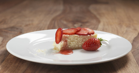 part of strawberry cheesecake on plate on wood table, 4k photo