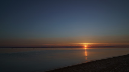 Fototapeta na wymiar orange sunset over baltic sea with clear sky and clouds near sun, summertime photo