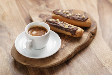 fresh espresso and eclairs with hazelnuts, sweet morning breakfast