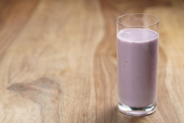 blueberry yogurt in glass on wood table, with copy space