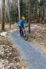 Obraz premium Mountain biking women riding on bike in early spring mountains forest landscape. Woman cycling MTB enduro flow trail track. Outdoor sport activity.