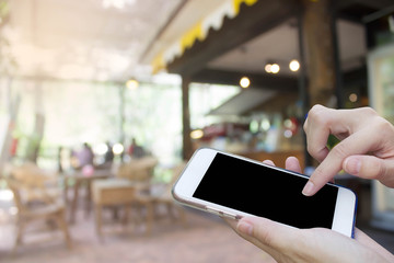 Woman using touch screen mobile phone with Coffee shop blur background