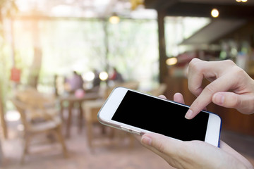 Woman using touch screen mobile phone with Coffee shop blur background