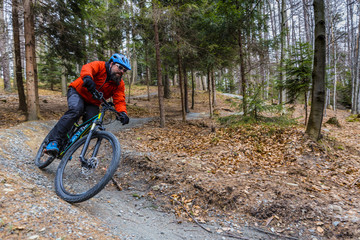 Fototapeta premium Mountain biker riding on bike in early spring mountains forest landscape. Man cycling MTB enduro flow trail track. Outdoor sport activity.