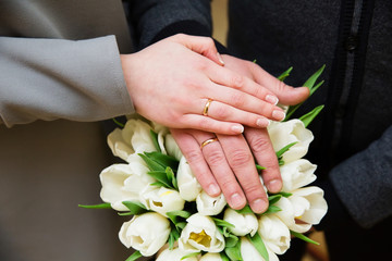 Hands of the groom and bride with rings and bridal bouquet