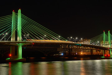 Fototapeta premium Portland Tilikum Crossing Bridge night view with blurred train and colored lights and Willamette River with reflection.