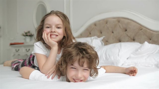 Brother And Sister Relaxing Together in the Bed. Cute Children are Having Fun in the Bedroom in the Morning.