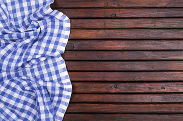 Dark wooden table with blue checkered tablecloth, top view with copy space