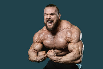 Fototapeta premium Handsome fit caucasian muscular man flexing his muscles in gym