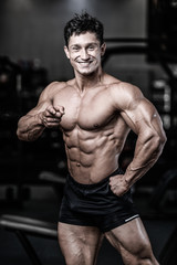 Fototapeta na wymiar Handsome caucasian muscular man on diet point fingers in gym..