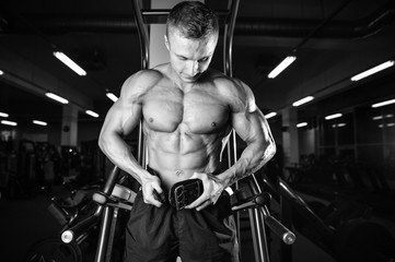 Fototapeta na wymiar Brutal bodybuilder powerful training arms, pectorals and shoulders in gym