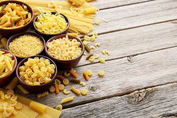 Different kinds of pasta in bowls on grey table
