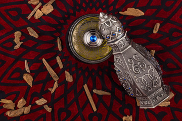 Silver Oriental Artisitc Arabian Oud Perfume / Arabian Oud Perfume with Oud Scented Wood burned in the background with Scented Smoke in the Air 