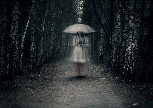 Ghost woman stands on a dark path in the forest