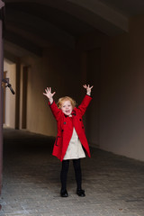 Portrait of a beautiful little girl with red hair in a red coat