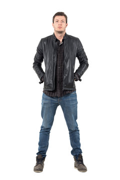 Front of young man in jeans and jacket with hands in pockets looking at camera. Full body length portrait isolated over white studio background. 