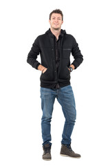 Naklejka premium Happy young relaxed smiling man with hands in hooded jacket pockets looking at camera. Full body length portrait over white studio background.