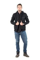 Fototapeta premium Confident young casual male in hooded black winter jacket and jeans. Full body length portrait over white studio background.