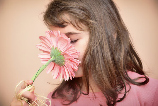 Cute young girl with closed eyes smelling a flower