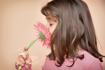 Cute young girl with closed eyes smelling a flower