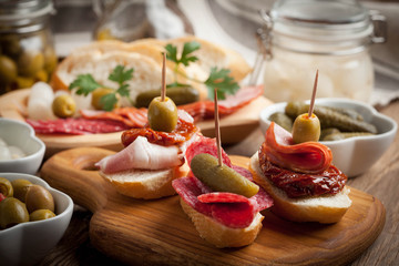 Tapas with sliced sausage, salami, olives and parsley.