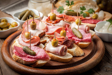 Tapas with sliced sausage, salami, olives and parsley.