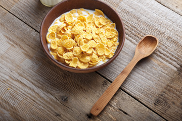 Cornflakes cereal and milk in a clay bowl.