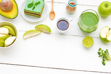 Healthy green meal on a white table. Green breakfast or lunch concept: scrambled eggs with spinach, green smoothie, matcha cake, black coffee, brown sugar, peanut butter toasts, apples. Top view.