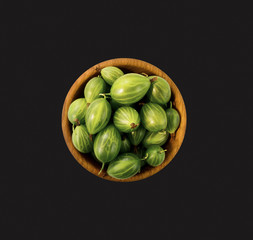 Gooseberry fruit isolated on black background. Gooseberry in a wooden bowl with copy space for text. Top view.