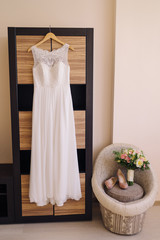 Bridal morning details. Beautiful bouquet of yellow and pink flowers, white wedding dress and leather shoes.