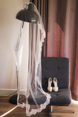 Bridal shoes on high heels and veil decorated with lace. Vertical wedding composition.