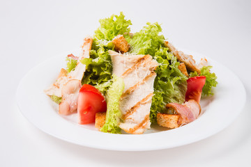 salad with bacon, tomatoes and croutons on a white plate (close)