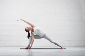 Young flexible woman practicing yoga indoors