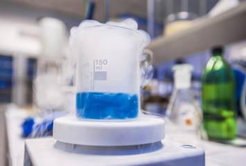 Blue liquid freezing in beaker with chemistry student at the back