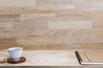 Coffee cup with notebook on wood table.