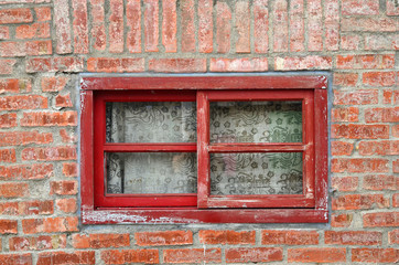 An old window on the brick wall with red wooden frames.