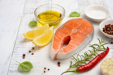 Fresh raw salmon steak with lemon, olive oil and spices on rustic wooden background. Ingredients for making healthy dinner. Healthy diet concept. Selective focus, copy space.