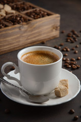 Cup of fresh coffee with coffee beans on dark background, selective focus