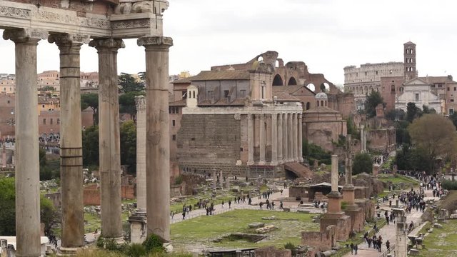 View of Roman Forum ruins in Rome, timelapse pan and zoom in from left to right with Colosseum in background and many tourist in the site