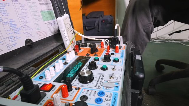Electrician testing electrical power with special equipment at industrial factory. 4K.