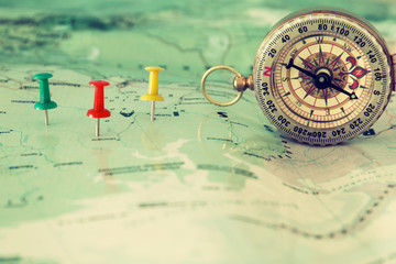 pins attached to map, showing location or travel destination and old compass.