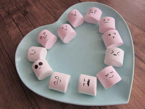 bowl of pink and white marshmallows on a wooden floor hearted