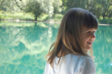 portrait of smiling little girl sitting by the river