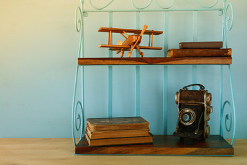 Vintage shelf with old wooden plane toy, books and decorative camera.