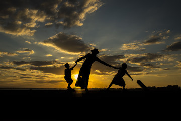 Silhouette of mother and children. Are playing happily together. The backdrop is the sunset.