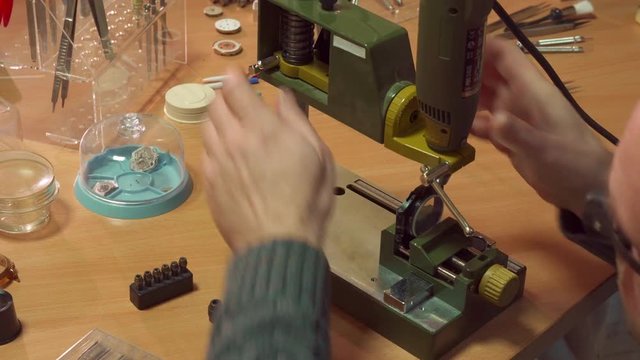 Hairless watchmaker customizing drill press at the workshop. Caucasian man change the height of entire drill head. Middle aged male repairer winding knob to change the position of press table