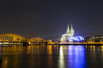Obraz premium Cologne Cathedral (German: Kolner Dom, officially Hohe Domkirche St. Peter und Maria) and Hohenzollern Bridge across the Rhine, Germany, at dusk